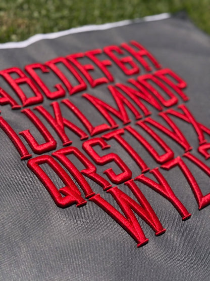 Red embroidered letters on a gray fabric background