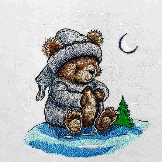 Embroidered illustration of a cute teddy bear wearing a winter hat and scarf, sitting under a crescent moon on a snowy ground with a small pine tree, original EmbroMania design.