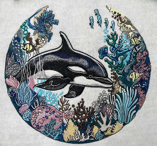 Embroidered design featuring an orca whale and bioluminescent coral reef.