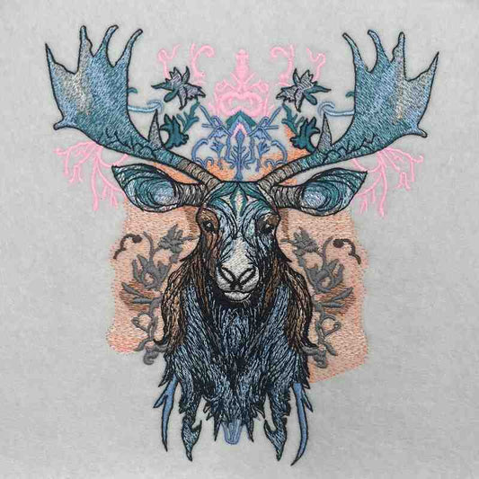 A stitched embroidery design of a moose head with ornate antlers and a floral pattern in blue, gray, and pink colors on a beige background.
