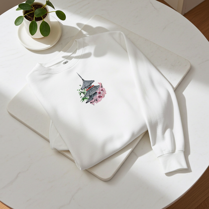 White unisex crewneck sweatshirt with pagoda and sakura cherry blossom embroidery design, flat lay on marble table with plant and soft sunlight.