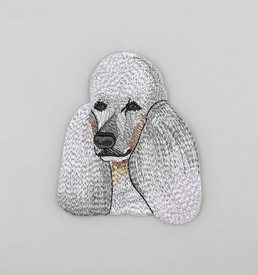 Embroidered design of a poodle on a grid background