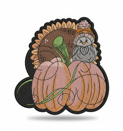 Embroidered design of a bird in a pumpkin with a white background