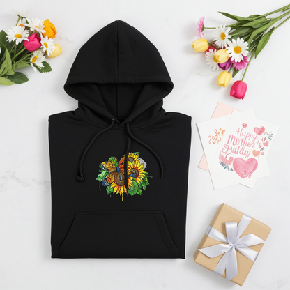 Black premium hoodie with Radiant Sunflower Butterfly embroidery featuring an orange butterfly over bright yellow sunflowers and green leaves, folded flat with flowers, Mother’s Day cards, and a wrapped gift, original EmbroMania artwork.