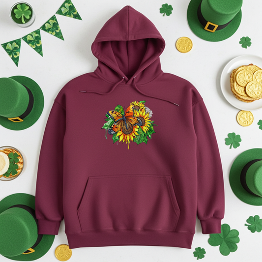 Burgundy premium hoodie with Radiant Sunflower Butterfly embroidery featuring an orange butterfly over bright yellow sunflowers and green leaves, styled with shamrock decorations, green hats, and gold coins, original EmbroMania artwork.