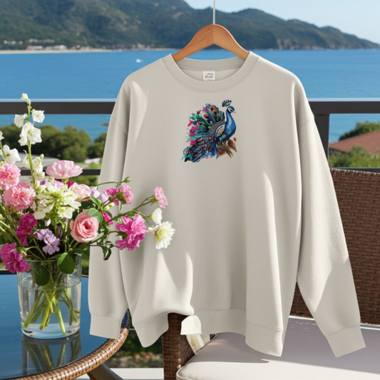 Mint Green  unisex crewneck sweatshirt with regal peacock embroidery design, hanging on hanger on balcony with ocean view and flowers.