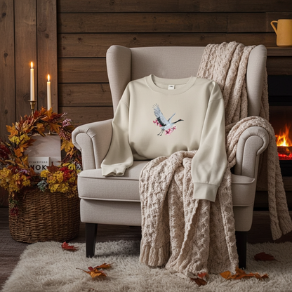 Mint Green  unisex crewneck sweatshirt with sakura crane embroidery design, styled on armchair with cozy knit blanket and warm fireplace setting.