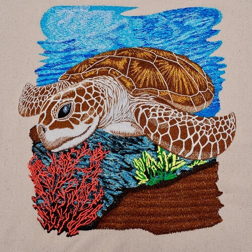 Embroidered sea turtle swimming above a coral reef with red coral and green sea plants on a blue ocean background, original EmbroMania design.