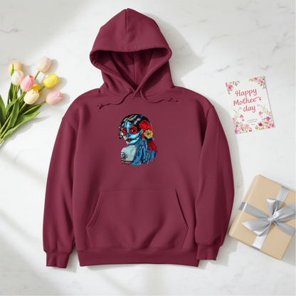 Burgundy premium hoodie with Sugar Skull Lady embroidery featuring a Día de los Muertos portrait in blue and red tones with floral accents, styled with tulips, a Mother’s Day card, and a wrapped gift, original EmbroMania artwork.