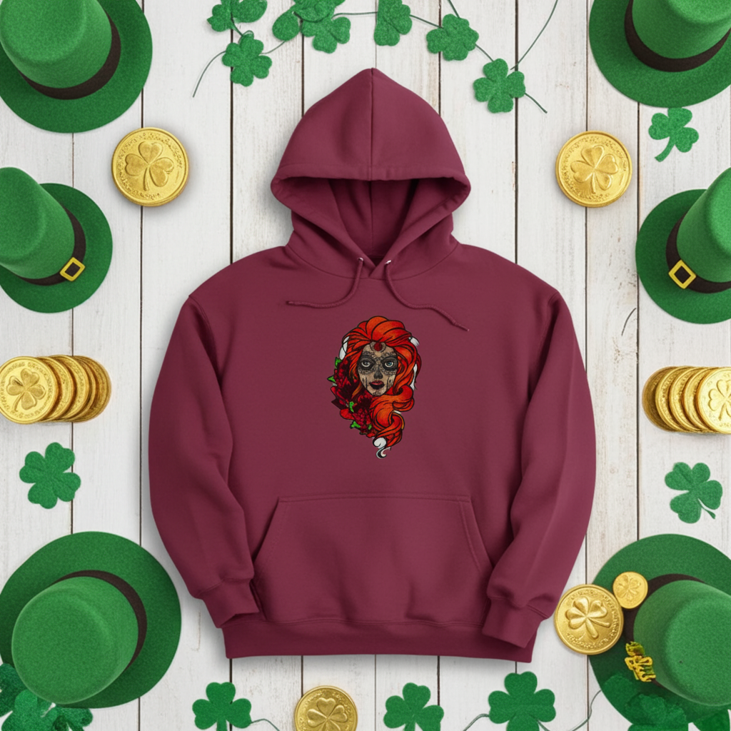 Burgundy premium hoodie with Sugar Skull Rose Girl embroidery featuring a sugar skull portrait with bright orange hair and red roses, styled on a wooden background with shamrock decorations, green hats, and gold coins, original EmbroMania artwork.