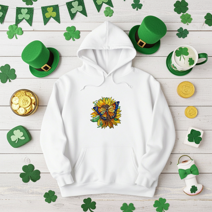 White premium hoodie with Sun-Kissed Butterfly & Sunflower embroidery featuring a blue and orange butterfly on a golden sunflower with green leaves, styled on a wooden background with shamrock decorations, green hats, and gold coins, original EmbroMania artwork.