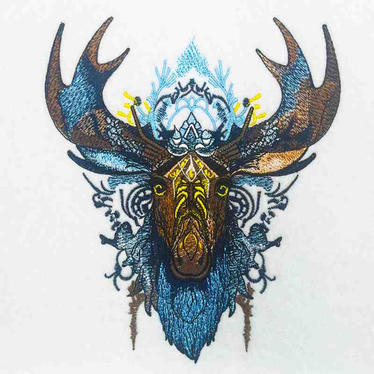 Close-up of Tribal Moose embroidery design featuring a moose head with bold antlers, detailed tribal linework, and stitched textures in deep blue, brown, and gold tones on a light fabric background, original EmbroMania artwork.