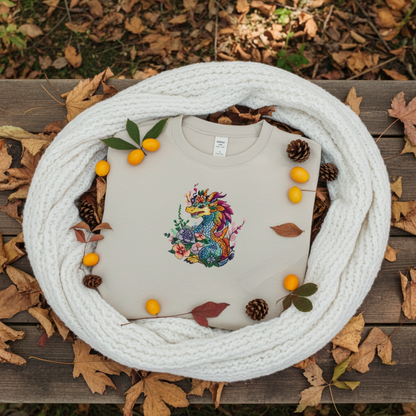 Mint Green unisex crewneck sweatshirt with vivid bloom dragon embroidery design, flat lay with cozy knit scarf, autumn leaves, pinecones and berries.