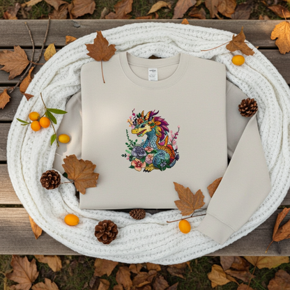 Mint Green unisex crewneck sweatshirt with vivid bloom dragon embroidery design, flat lay with cozy knit scarf, autumn leaves, pinecones and berries.