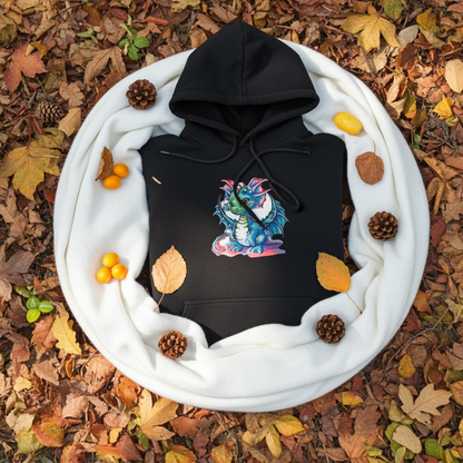 Black hoodie featuring a whimsical blue dragon embroidery design with big eyes and detailed wings, styled folded inside a white knit scarf on autumn leaves with pinecones and small berries, original EmbroMania artwork.