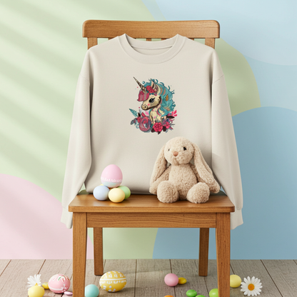 Mint green unisex crewneck sweatshirt with whimsical unicorn and floral embroidery design, hanging on chair in pastel Easter-themed setup with bunny plush and eggs.