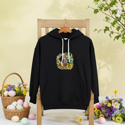 Black hoodie featuring a wild fox and floral wreath embroidery design on the chest, displayed on a wooden chair with spring flowers and pastel eggs in the scene, original EmbroMania artwork.