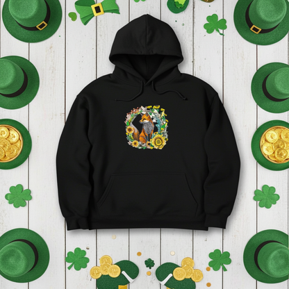 Black hoodie featuring a wild fox and floral wreath embroidery design on the chest, styled on a St. Patrick’s Day themed background with green hats, shamrocks, and gold coins, original EmbroMania artwork.