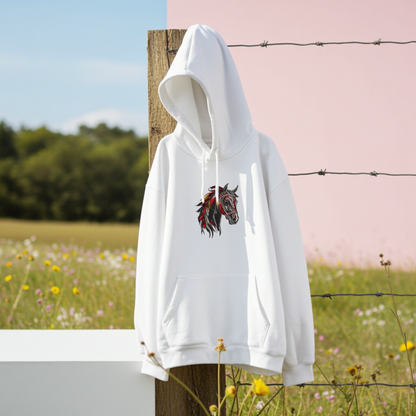 White unisex pullover hoodie with wild spirit horse head embroidery in black, red and gold, hanging outdoors on fence post with meadow background.