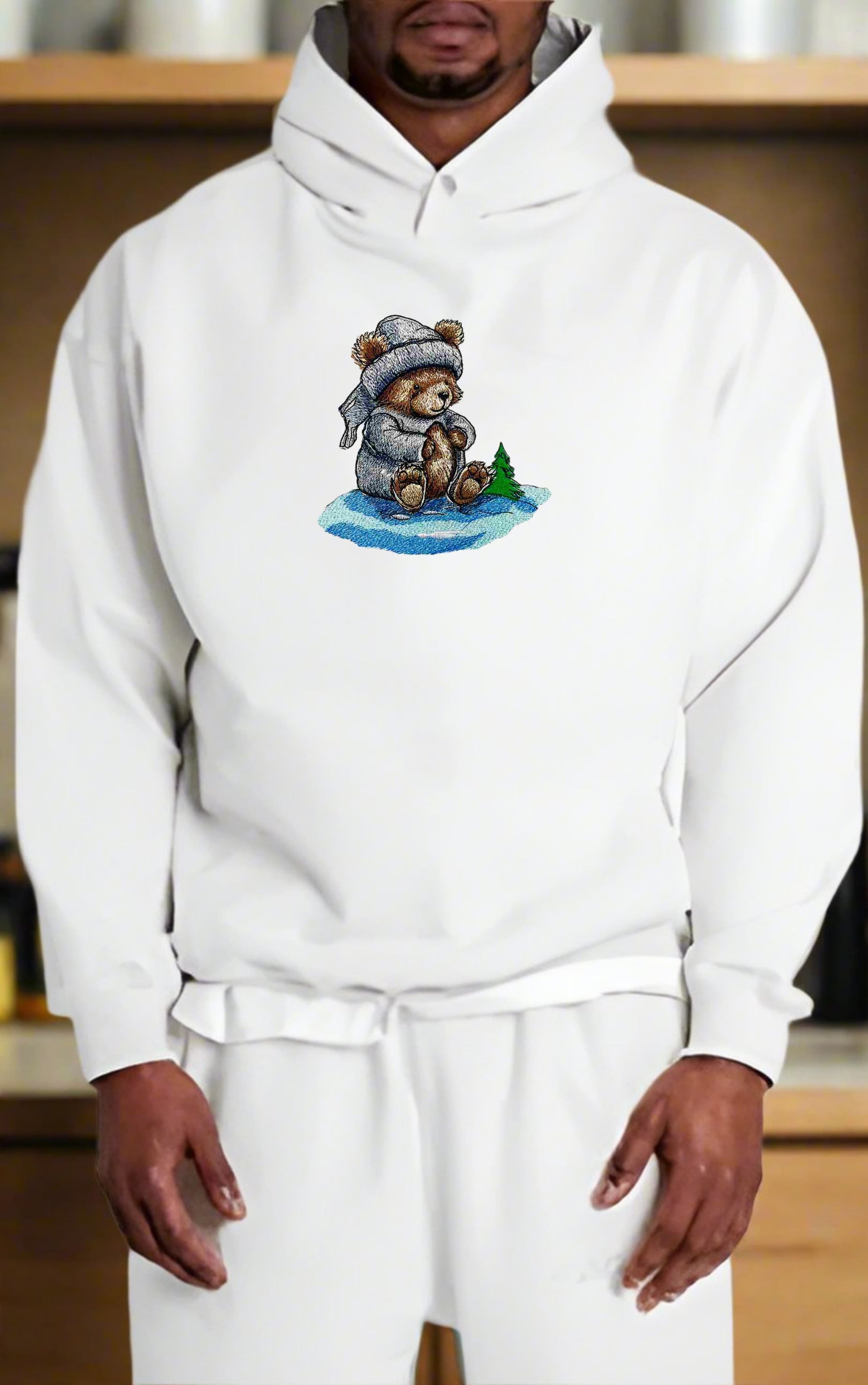 Person wearing a white hoodie with a teddy bear graphic on a wooden shelf background