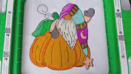 Embroidered autumn design featuring a whimsical gnome with a long beard and colorful hat waving beside two large pumpkins. Perfect for fall sweatshirts, clothing, and seasonal hoodies 

